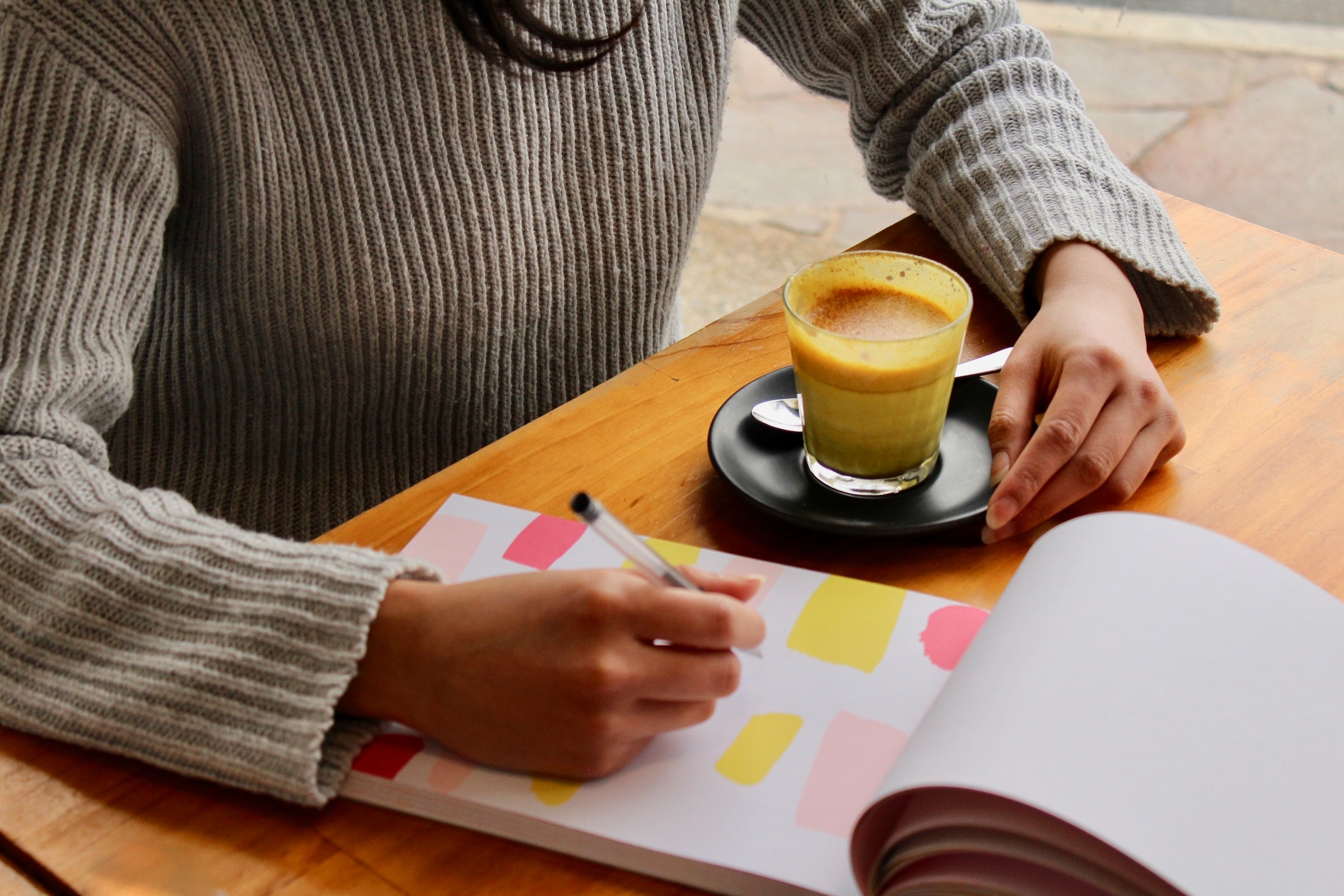 Person writing in a notebook, Meal Planning, while having a coffee